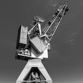 Black and white photo of an industrial crane at Hamburg's port, showcasing urban architecture.